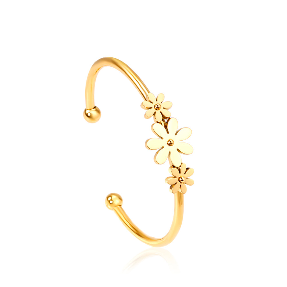 Gold colored hard bracelet with three small flowers of different sizes