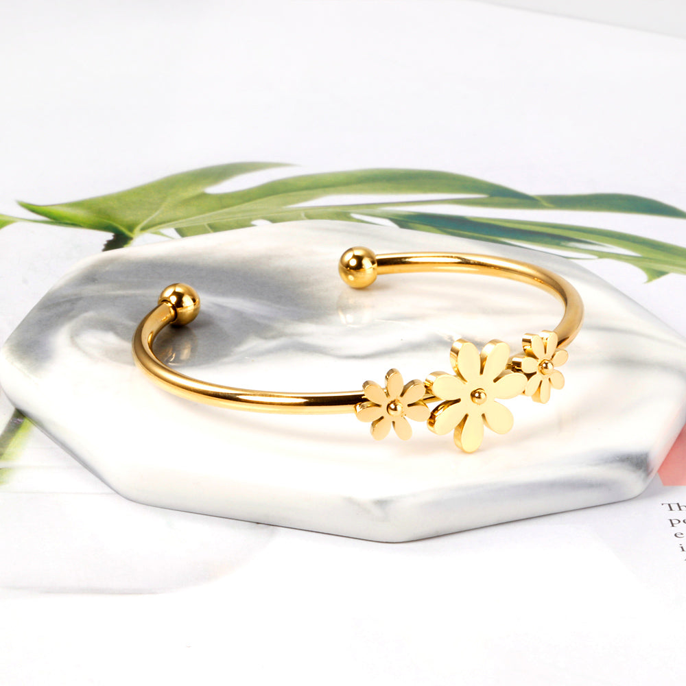 Gold colored hard bracelet with three small flowers of different sizes
