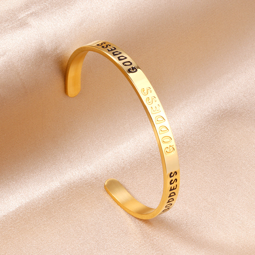 Gold colored hard bracelet with GODDESS printed on it